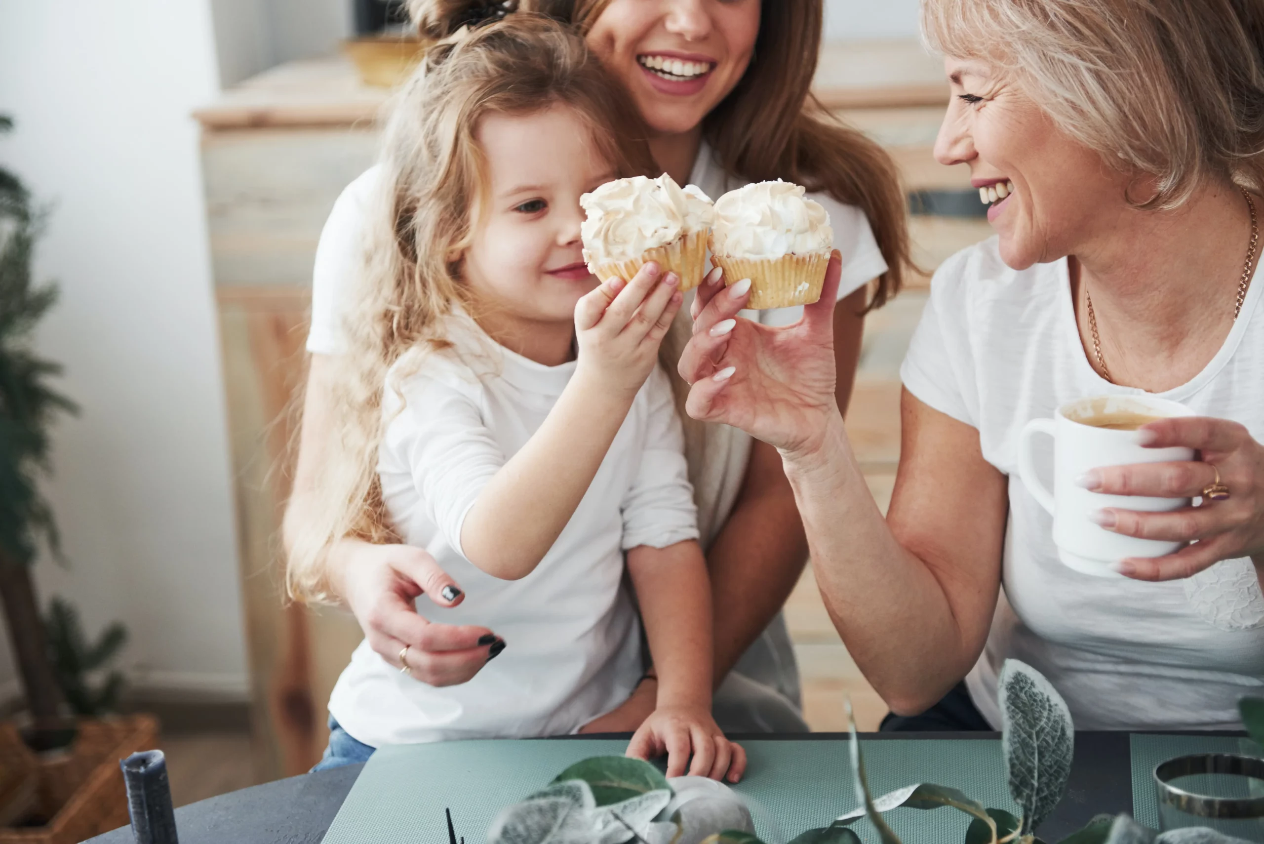 little girl with her mother and grandmother eating cakes